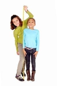 Girl measures another girl with a yardstick