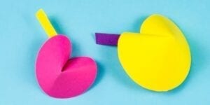 Predicting fortune cookie crafts showing a paper folded like a fortune cookie and a piece of paper with the prediction hanging out the side.