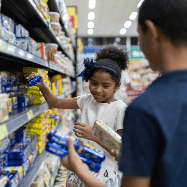 A little girl with a male adult shopping for ingredients so they can learn math while baking