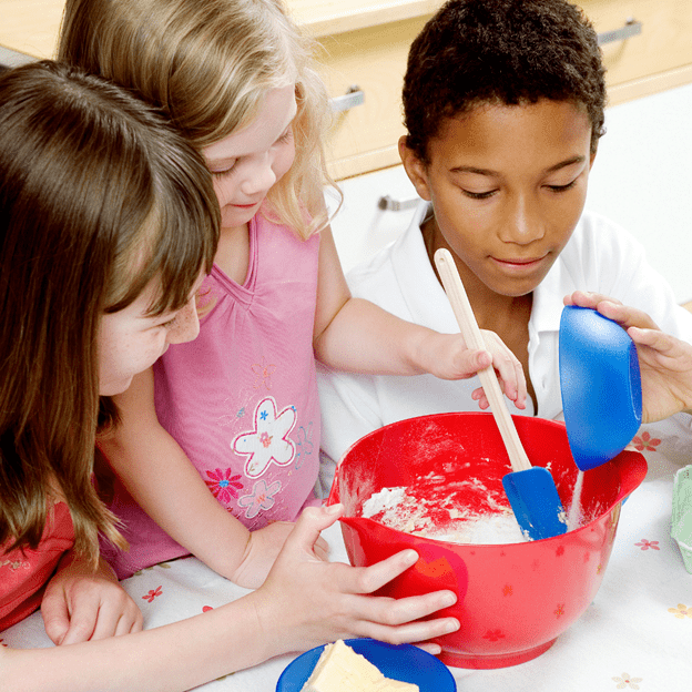 three children are mixing ingredients to learn math while cooking in school
