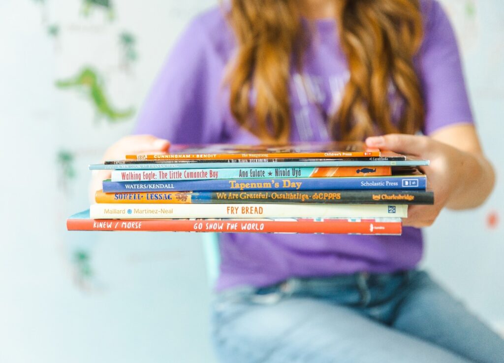Woman holding picture book recommendations for national native american history month.